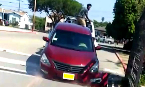 A man struggles to remove his Nissan Altima from a moving tow truck in California.